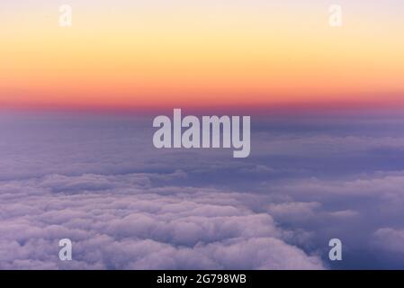Dramatischer Sonnenaufgang über den Wolken. Violettes Licht der Morgendämmerung, warme Rot- und Orange-Töne, Farbverlauf. Perfekter Hintergrund, keine Menschen Stockfoto