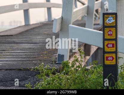 Impressionen einer Frühjahrswanderung bei Sonnenaufgang und Nebel in Südholland in der Region Alblasserwaard Vijfheerenlanden bei Kinderdijk: Wegweiser an einer Brücke Stockfoto