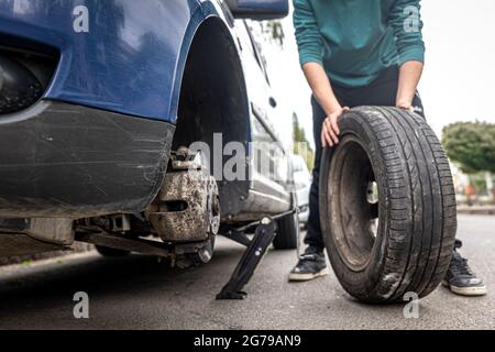 Mechanisches Schrauben oder Lösen des Wechselrads eines Autos durch einen Schraubenschlüssel Mechaniker bei der Arbeit, wenn ein Rad an einem Auto gewechselt wird. Stockfoto