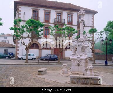 FUENTE DE LOS TRES CAÑOS Y CASONA EN LA PLAZA DEL PUEBLO. AUTOR: DOMENECH Y MONTANER LLUIS. Lage: AUSSEN. Comillas. Kantabrien. SPANIEN. Stockfoto