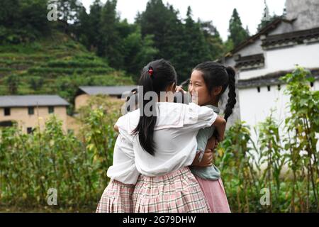 (210712) -- XIUNING, 12. Juli 2021 (Xinhua) -- Zhang Qingyu umarmt ihre Freunde im Dorf Qingxi, der Gemeinde Huangjian in der ostchinesischen Provinz Anhui, 10. Juli 2021. „Ich würde diese zwei Tage der Trennung gerne überspringen, wenn ich könnte.“ Xu schrieb auf ihr Konto in einem sozialen Netzwerk, als sie kurz vor der Beendigung ihres Dienstes in der Gemeinde Huangjian stand: Xu Xiaochan und Zhang Jianming zusammen mit ihrer Tochter Zhang Qingyu, 2019 zog das Paar nach Huangjian in der Stadt Huangshan, als es beschloss, an einer Kampagne teilzunehmen, um medizinische Versorgung für die dortigen Dorfbewohner zu gewährleisten. Der medizinische Dienst im ländlichen Raum, der für zwei Ye dauert Stockfoto