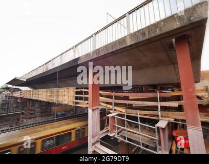 12. Juli 2021, Brandenburg, Potsdam: Ein S-Bahn fährt unter einem der Segmente der alten Brücke auf der Baustelle der Hochbrücke der Landstraße L40 Nuthestraße entlang. Aufgrund von Platzmangel werden die rund 30 Meter langen und 600 Tonnen schweren Abschnitte aus Beton und Verstärkungsstahl in mehreren Teilschritten hinter dem Abutment der Friedrich-Engels-Straße mittels Hydraulik gezogen, wo der alte Überbau zerkleinert und abtransportiert wird. Die Sanierung der Hochstraßenbrücke soll im Oktober 2022 abgeschlossen werden. Foto: Soeren Sache/dpa-Zentr Stockfoto