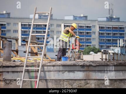 12. Juli 2021, Brandenburg, Potsdam: Ein Arbeiter bohrt Löcher am Rand eines der Segmente der alten Brücke auf der Baustelle der Hochbrücke der Landstraße L40 Nuthestraße. Aufgrund von Platzmangel werden die rund 30 Meter langen und 600 Tonnen schweren Abschnitte aus Beton und Verstärkungsstahl in mehreren Teilschritten hinter dem Abutment der Friedrich-Engels-Straße mittels Hydraulik gezogen, wo der alte Überbau zerkleinert und abtransportiert wird. Die Sanierung der Hochstraßenbrücke soll im Oktober 2022 abgeschlossen werden. Foto: Soeren Sache/dpa-Zentr Stockfoto