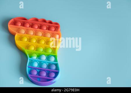Farbenfrohe Antistress-Sensory-Pop-it-Spielzeuge in Fußform auf blauem Hintergrund. Stockfoto