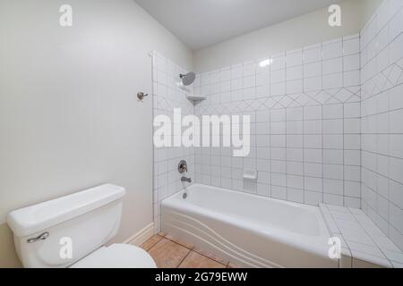 Innenraum eines Badezimmers mit Toilettenschüssel und Nische Badewanne Dusche Kombination mit Fliesen Stockfoto