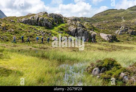 Eine Reihe von Orientierungsläufern, die am Inomminate Tarn auf Haystacks entlang gingen, fiel über Buttermere im Lake District in Großbritannien Stockfoto