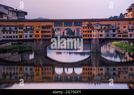 Nahaufnahme der Ponte Vecchio und des Arno Flusses, Florenz, Toskana, Italien. Morgengrauen, Sonnenaufgang mit goldenem Licht und einer lebendigen, farbigen Architektur. Stockfoto