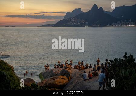 Ein magischer Ort: Die Menschen applaudieren, wenn die Sonne am Arpoador-Felsen untergeht, mit Blick auf den Strand von Ipanema und die Berge von Morro Dois Irmaos und Leblon im Hintergrund. Kamera: Leica M10 Stockfoto