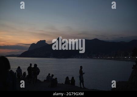 Ein magischer Ort: Die Menschen applaudieren, wenn die Sonne am Arpoador-Felsen untergeht, mit Blick auf den Strand von Ipanema und die Berge von Morro Dois Irmaos und Leblon im Hintergrund. Kamera: Leica M10 Stockfoto