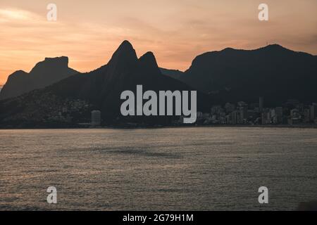 Ein magischer Ort: Die Menschen applaudieren, wenn die Sonne am Arpoador-Felsen untergeht, mit Blick auf den Strand von Ipanema und die Berge von Morro Dois Irmaos und Leblon im Hintergrund. Kamera: Leica M10 Stockfoto