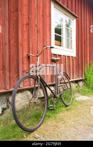 Altes Fahrrad, das an der Holzwand eines Hauses gelehnt ist Stockfoto