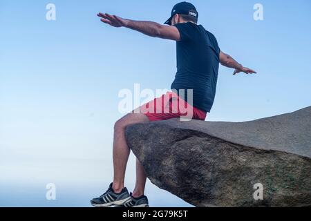 Ein Mann, der den Blick auf die wilden Strände von einem Felsen auf dem Gipfel des Berges Pedra do Telegrafo, Barra de Guaratiba, Rio de Janeiro, Brasilien, genießt. Aufgenommen mit Leica M10 Stockfoto