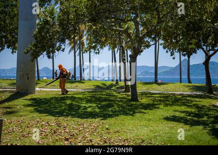 Arbeiter, die im Flamengo Park - Parque Atro do Flamengo - in Rio de Janeiro ein schweres Laubgebläse betreiben. Ein weitläufiger Strandpark mit Sportplätzen, Wander-/Radwegen, einem Skatepark und einem Kunstmuseum. Stockfoto