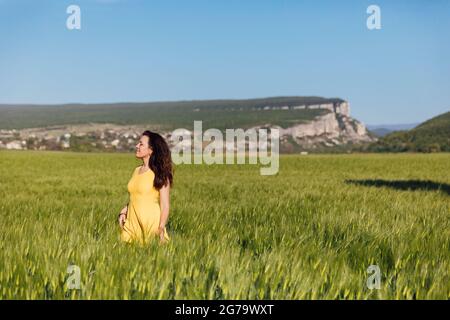 Eine Frau auf einem Feld aus grünem Weizen vor der Ernte Stockfoto