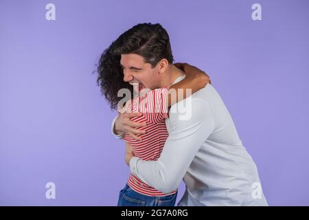 Sweet multi-ethnischen Paar umarmt auf lila Studio-Hintergrund. afroamerikanische Frau und weißer Mann sehen isoliert umarmt und lächelnd aus. Sie sagte ja. Stockfoto