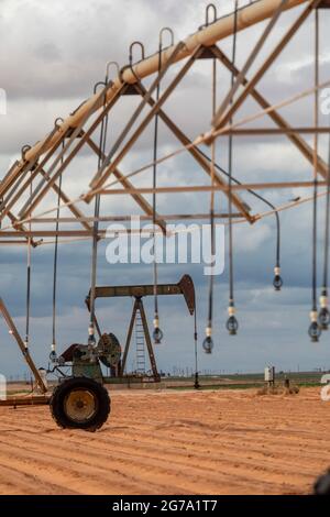 Plains, Texas - ein Ölbrunnen in der Nähe von Bewässerungsanlagen auf Ackerland im Permian Basin. Stockfoto