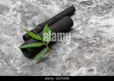 Bambus Aktivkohle Sticks und grünes Blatt isoliert auf grauem Hintergrund Stockfoto