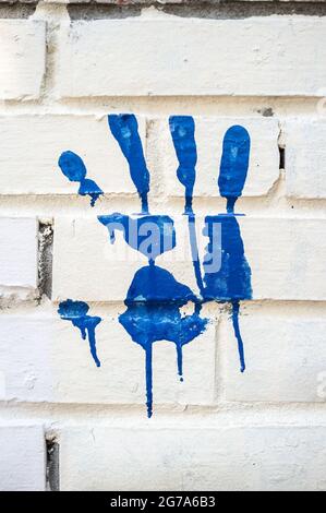 Der Palmdruck wurde in blauer Farbe auf einer weißen Ziegelwand hergestellt. Tolle Idee. Abstrakter Hintergrund. Stockfoto