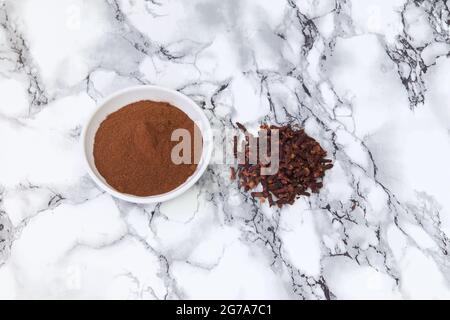 Ganze Nelken und gemahlene Nelken in einer Schüssel Stockfoto