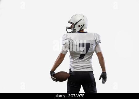 Nahaufnahme eines amerikanischen Fußballspielers mit isoliertem Ball auf weißem Studiohintergrund. Rückansicht Stockfoto