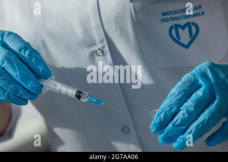 Eine Krankenschwester in der Moskauer Klinik bereitet eine Spritze für eine Injektion im medizinischen Büro vor. Auf der Inschrift neben einem Logo steht: „Moskauer Klinik“ Stockfoto
