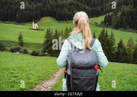 Wanderfrau mit Rucksack Genießen Sie den Blick auf die St. Johann Kirche im Val di Funes Tal, Dolomiten, Italien, Europa Stockfoto