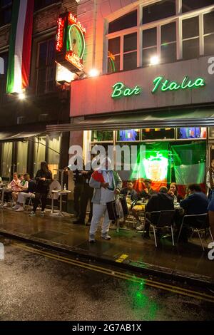 Fußballfans, die das Spiel vor der Bar Italia in Soho auf ihrem Telefon verfolgen, während das EM 2020-Finale zwischen England und Italien im Gange ist. Stockfoto