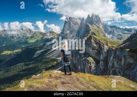 Erwachsene Frauen mit Rucksack genießen die Landschaft des Seceda-Gipfels in den Dolomiten Alpen, Geislergebirge, Südtirol, Italien, Europa. Reiseurlaubskonzept Stockfoto