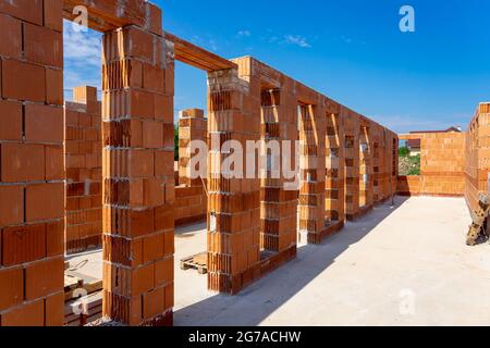 Haus unter Baubedingungen mit modernen Backsteinwänden und Löchern für Türen und Fenster Stockfoto