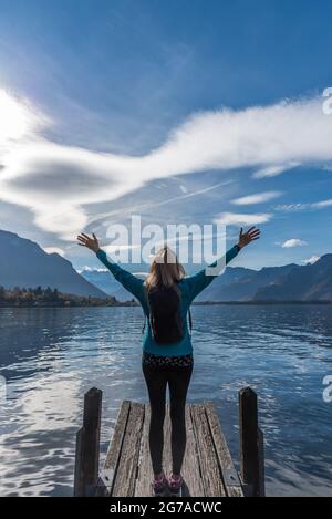 Unerkannte Frau, die ihre Arme hob und die Aussicht auf die Berge und den See genoss. Stockfoto