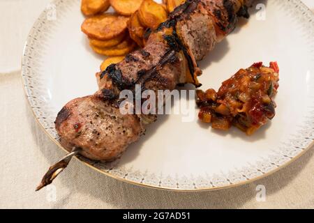 Gegrilltes Schweinefleisch und Lammspieß oder Kebob mit BBQ-Sauce und dünnen, knusprigen Kartoffelscheiben Stockfoto