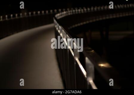 Parkweg bei Nacht. Das Licht der Fanaren auf der Uferbrücke. Weg im Dunkeln. Platz für einen Spaziergang. Stockfoto