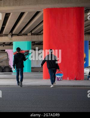 Rückansicht von Wandmalern, die mit Farbeimern laufen Stockfoto