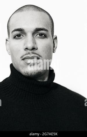 Porträt eines jungen Mannes mit gemischter Rasse, der mit körnigem Film auf weißem Hintergrund gedreht wurde. Stockfoto