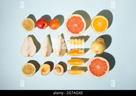 Ordentlich angerichtet frisches Obst auf blauem Hintergrund. Minimale flache Verlegung. Kontrastierende Schatten. Stockfoto