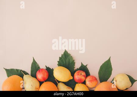 Sommerfrüchte auf Blättern auf hellorangefarbenem Hintergrund. Stockfoto