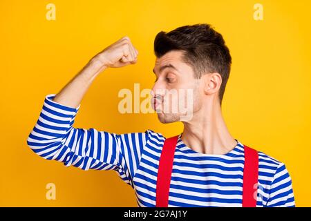 Profil Seite Foto von jungen schönen Mann Seemann zeigt küssende Bizeps Muskeln isoliert auf gelbem Hintergrund Stockfoto