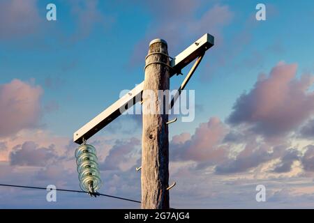 Foto eines hölzernen Telefonpfostens und Kabel vor einem blauen Himmel Stockfoto