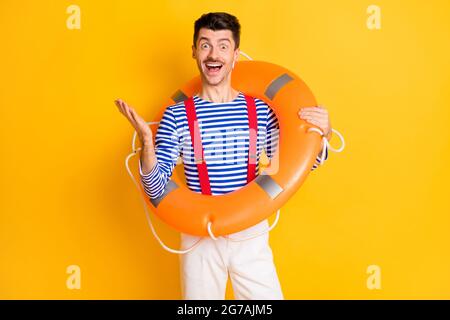 Foto von jungen gut aussehenden positiv fröhlich erstaunt aufgeregt Mann Seemann mit großen Boje isoliert auf gelbem Hintergrund Stockfoto