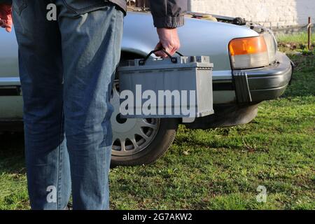 Eine Frau trägt eine Autobatterie zur Montage in einem Auto. Stockfoto