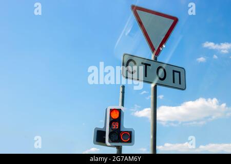 Verkehrsschild Give Way, Stop-Stop, elektronische Ampel mit Countdown, gegen den blauen Himmel mit Reflexion Stockfoto