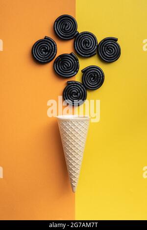 Spirale aus Süßholz und Eiskegel auf buntem Hintergrund. Draufsicht. Stockfoto