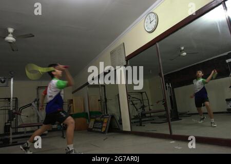 Ein junger Badmintonathlet übt verschiedene Schläge und Schritte vor einem großen Spiegel im Jaya Raya Badmintonclub in Jakarta, Indonesien. Stockfoto