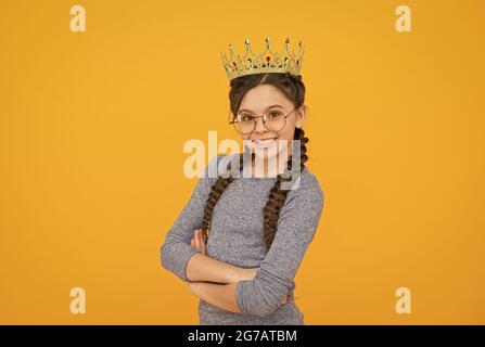 Ihr eigener Chef zu sein. Kleiner Boss, gelber Hintergrund. Glückliches Kind tragen Krone. Schönheitskönigin. Abschlussball-Party. Konzept des großen Chefs. Ruhm und Triumph. Luxus Stockfoto