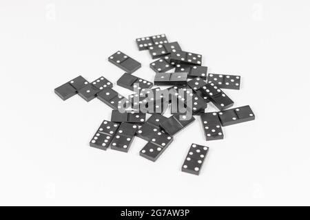 Schwarze und weiße Dominosteine werden auf einem weißen Holztisch verstreut gespielt. Selektiver Fokus. Nahaufnahme Stockfoto