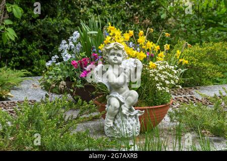 Deutschland, Baden-Württemberg, Blaustein-Lautern, Blumenschale mit Frühlingsblumen, Engelskulptur im Kirchhof der Evangelischen Marienkirche Stockfoto