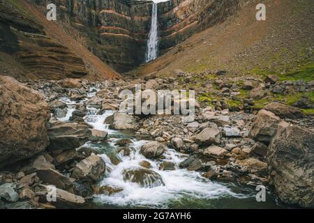 Hengifoss Wasserfall in Ostisland. Hengifoss ist der dritthöchste Wasserfall Islands und wird von basaltischen Schichten mit roten Tonschichten zwischen den basaltischen Schichten umgeben. Stockfoto