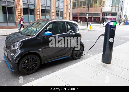 Black Smart forfour kleines Elektroauto, das an einer Ladestation auf einer Straße in der City of London in Großbritannien AUFLÄDT KATHY DEWITT Stockfoto