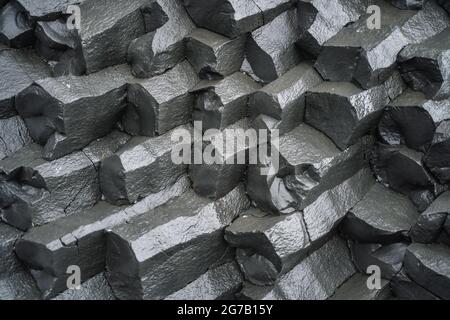 Nahaufnahme von Basaltsäulen am schwarzen Sandstrand. Island Stockfoto