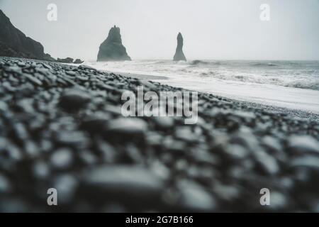 Steine an einem schwarzen Strand an einem launischen Tag in Island Stockfoto